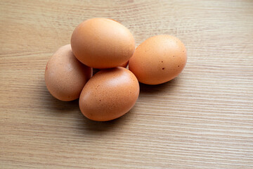 Fresh brown eggs on a rustic wooden kitchen countertop, illuminated by soft natural light, creating a warm and homely atmosphere. Perfect for food and farm-to-table concepts.