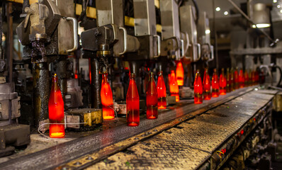Glass factory, production of glass containers. Molten glass is blown into molds. Robotics in industry. Modern technologies, robotic machines produce products. Technological work at the plant.
