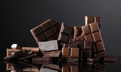 Broken bitter and milk chocolate bars on a black background.