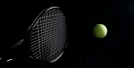 tennis balls and racket in a dark background