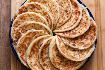 A plate of msemen with perfectly golden and flaky layers, arranged in a circle, exuding a fragrant aroma of spices.