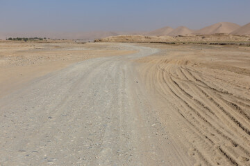 Gravel road winding through Ghurmach in Badghis Province, Afghanistan under clear skies