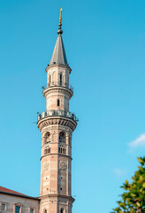 A tall minaret with a pointed dome and intricate architectural details against a clear blue sky