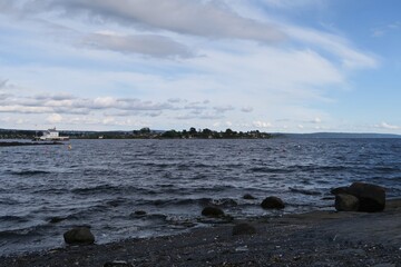 Wellen branden am Strand der Insel Bygdoy in Oslo. Im Hintergrund ist im Oslofjord der Leuchtturm...