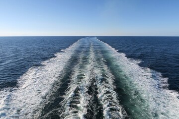 Die Fähre von Oslo nach Kopenhagen fährt en einem sonnigen Sommerabend im Skagerrak. Es ist ruhige See. Wo die Fähre  gefahren ist, zeigt das Heckwasser hinter dem Schiff.