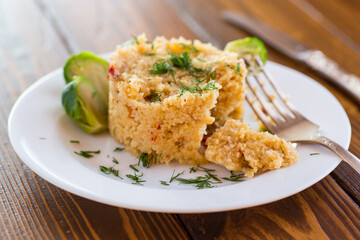 homemade cooked bulgur with Brussel sprouts in a plate, on a wooden table