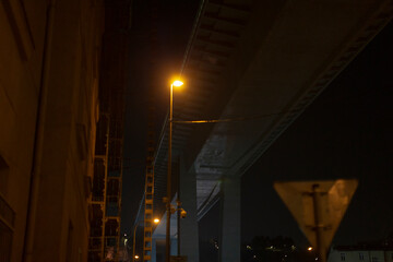 A street light shines brightly and illuminates the surrounding dark area beneath a bridge during...