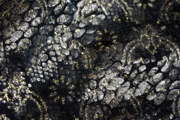 Black dark fabric background with gilding, gold flower patterns with reflective plastic scales.