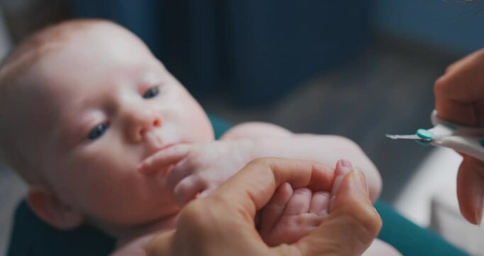 Mom clips her baby nails, focusing on the infant child safety and comfort