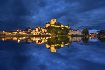 Burg in Österreich zur blauen Stunde  mit Spiegelung in einem See bei bewölktem Himmel