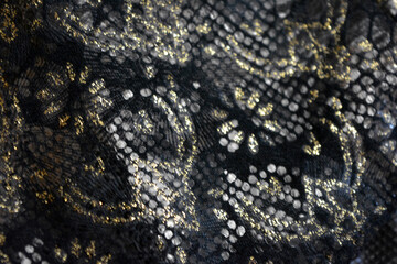 Black dark fabric background with gilding, gold flower patterns with reflective plastic scales.