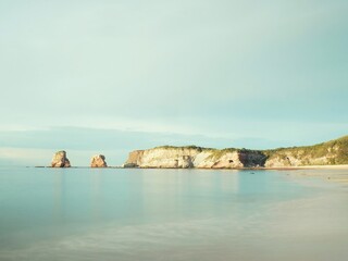 Beach with silky water and sunny cliff in the background. 