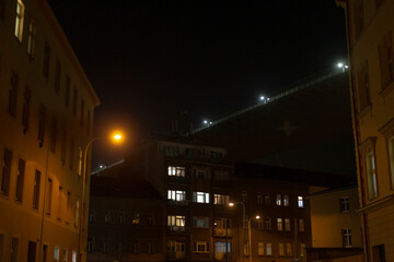 A bustling city street illuminated at night, featuring a bright street light prominently in the...