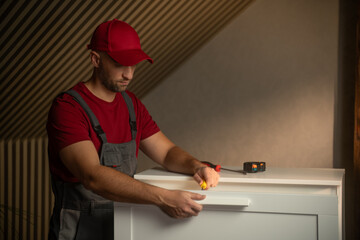 A skilled individual assembles a piece of furniture in a well-lit room. He uses various tools, demonstrating precision and efficiency during the process.