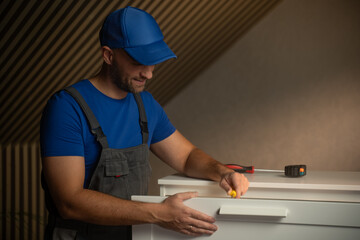Craftsman focuses on assembling a sleek drawer in a contemporary workspace. Tools are neatly arranged while natural light highlights the modern setup.