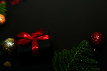 Deluxe holiday wishes concept. luxurious gift package, Christmas and New Year background on black. Decorative border of fir branches, Christmas balls and candy cane black backdrop text or ad space