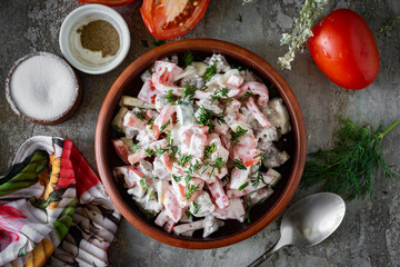 Salad with meat, tomatoes and cheese in a brown plate on a gray background. A breakfast dish. View from above. Close-up