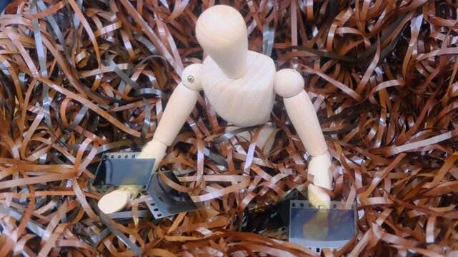 concept of the past, a wooden mannequin surrounded by unwound magnetic tape holds on his hands an old 35mm analog positives film slides artistic
