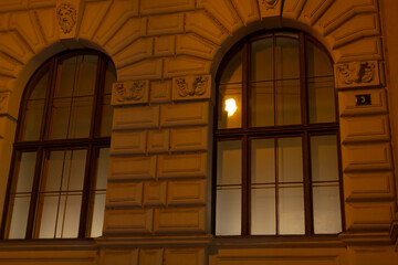 A lovely building features two beautifully designed arched windows complemented by a charming street light nearby, creating a warm atmosphere