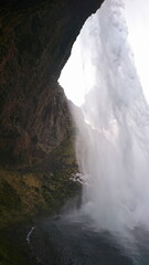 Iceland - 3.26.2018: View behind Seljalandsfoss from a cave in the cliff with water crashing down...