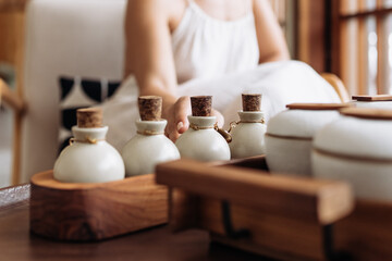Young woman chooses, tries natural organic essential oils for spa procedure. Skin care beauty rituals for body, soul. Aromatherapy cosmetics ads. Woman relaxing in massage spa salon, focus on bottles