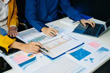 Business documents on office table with smart phone and laptop and two colleagues discussing data