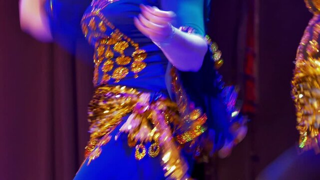 Dances. Two women in beautiful clothes with gilded jewelry are dancing a belly dance. Close-up, hand held. Siberia.