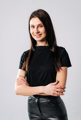 Young woman poses confidently in stylish outfit. A young woman smiles with arms crossed, showcasing...