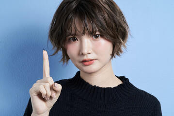 人差し指を立てるショートカットの女性