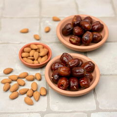 Obraz premium Dates and almonds in clay plates on stone tile background