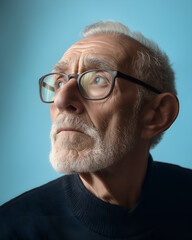 Fototapeta premium Senior man with an expression of deep thought on a soft blue backdrop