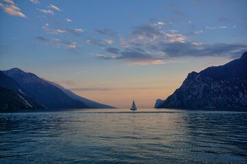 Single boat sailing into the sunset at Lago di Garda in Italy.