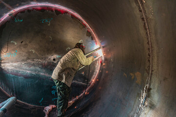Male worker wearing protective clothing and repair welding industrial construction oil and gas or...