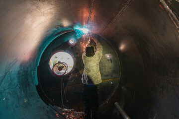 Male worker wearing protective clothing and repair welding industrial construction oil and gas or...