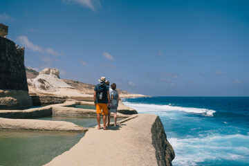 People are looking at beautiful seascape with traditional salt pans in Xwejni Bay on the island of...