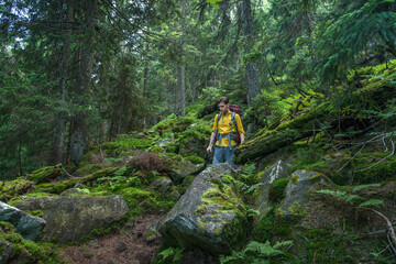 Young man with backpack in the deep forest enjoying hiking during the weekend.