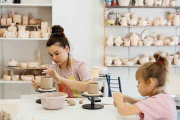 A mother and daughter bond during pottery crafting at a sunny studio