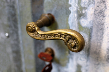 Vintage, decorative, golden door knob on weathered metal doors