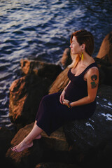 Fototapeta premium Pregnant girl at sunset by the sea