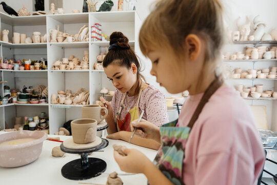 Young artists engaged in pottery making at a creative studio - Powered by Adobe