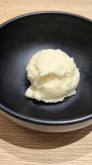 Mashed potatoes in a black cup on a wooden table