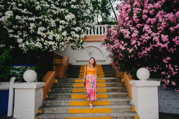 Pregnant girl in the park against the background of blooming oleander trees