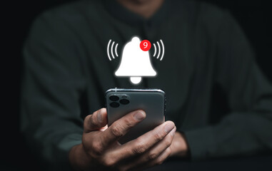 businessman's hand holds the mobile and presses the button of Notification bell Concept of Remote online alerts on the Application. A  button on mobile, unread message, or email notification..