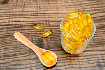 Vitamin capsules displayed in a glass alongside a wooden spoon