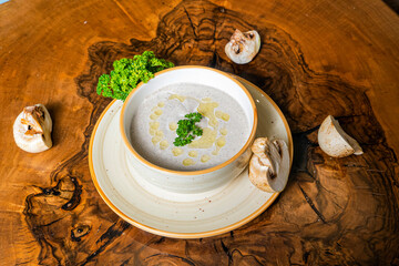 Delicious creamy soup garnished with parsley on a wooden table