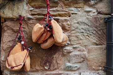 Traditional leather wine skins hanging on a rustic stone wall with red ropes in a village in Spain