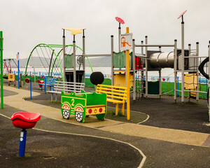 Adventure climbing frame with netting and steel tunnel and a little car in the foreground in a kiddies playground