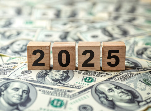 wooden blocks showing 2025 rest on one hundred dollar bills