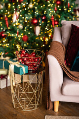 Christmas living room interior in studio apartment. Large decorated Christmas tree, sofa, plaid, gift boxes, fluffy carpet, light garlands. 