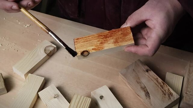 Male hands painting a piece of wood in carpentry workshop